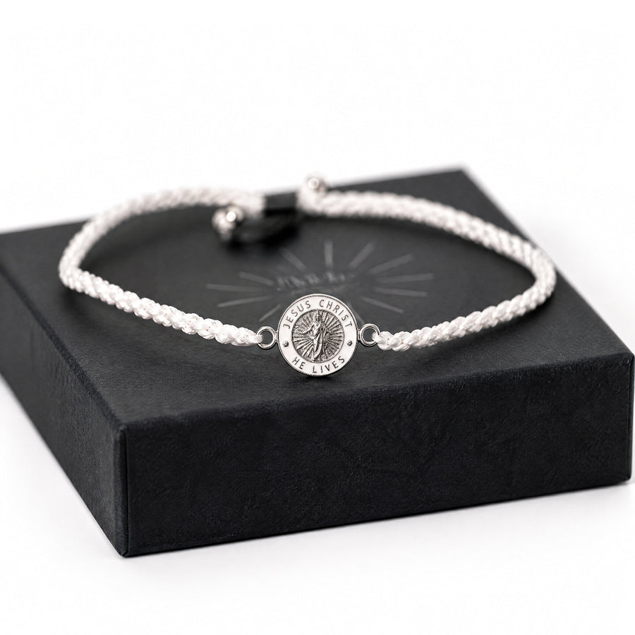 White cord He Lives bracelet with 11mm pendant on gift box