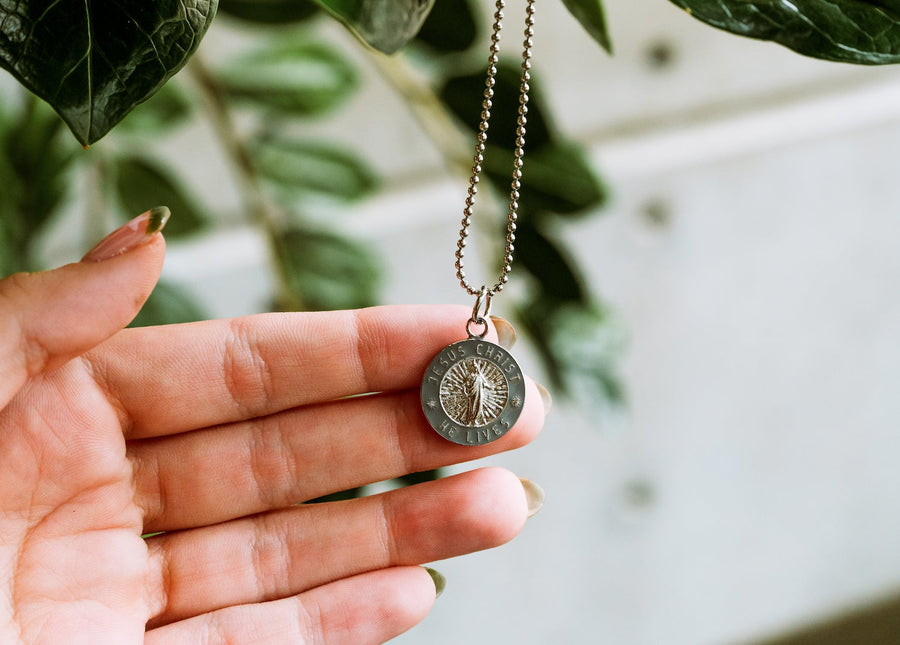 He Lives necklaces and gift boxes on textured stone